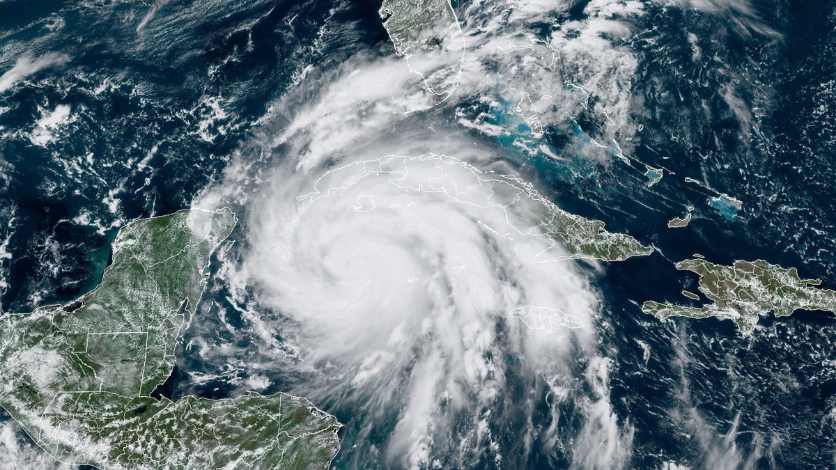 Hurricane Ian looks like a white swirling mass above dark blue ocean with green land masses below.