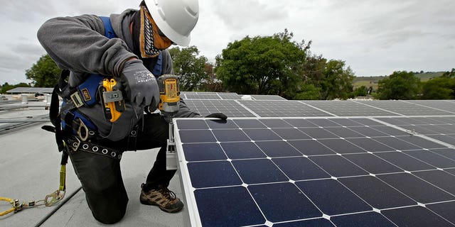 A worker installs a rooftop solar panel.