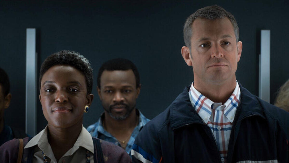 Two characters from From All Mankind stand shoulder to shoulder on an elevator looking straight ahead.