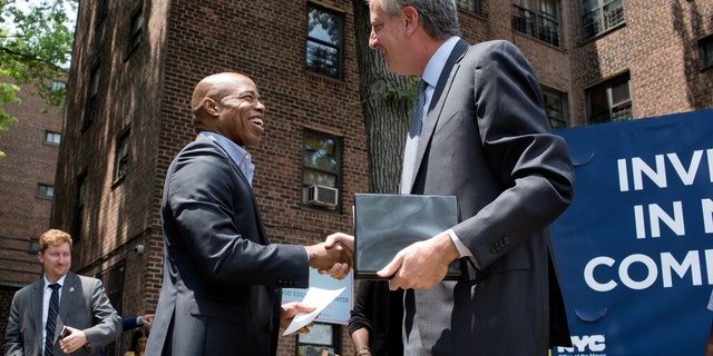 Public housing residents watch then-New York City Mayor Bill DeBlasio and Brooklyn borough president Eric Adams speak at a ceremony for the groundbreaking of a new community center in the Marcy Houses on June 11, 2018, in Brooklyn, New York. 