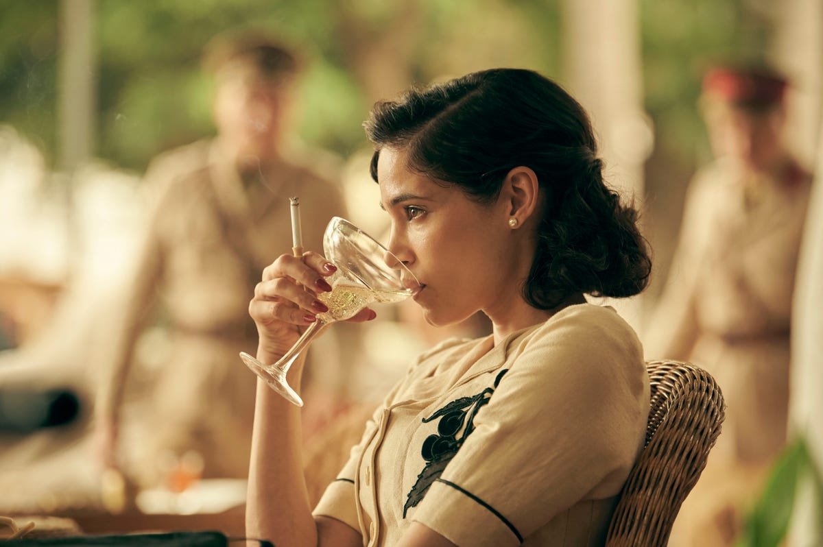 Sofia Boutella sips from a champagne saucer in Rogue Heroes.