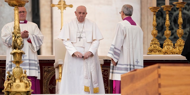 Pope Francis stands by the coffin of late Pope Emeritus Benedict XVI in St. Peter's Square during a funeral mass at the Vatican, Thursday, Jan. 5, 2023. 