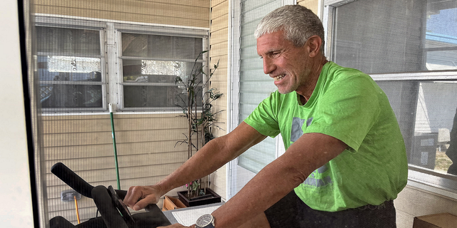 Rick Singer works out on a Peloton bike while being interviewed by the Bay Area News Group at his home in the Isle of Palms mobile home park in Saint Petersburg, Florida, on June 23, 2022. 