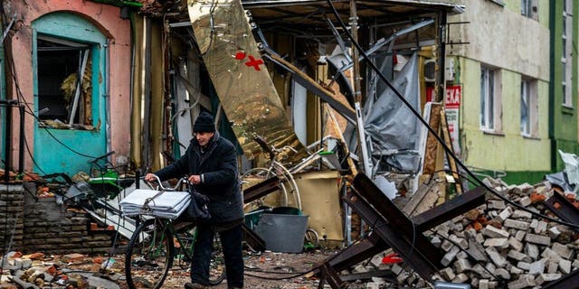 A resident pushes his bicycle past "hedgehog" tank traps and rubble, down a street in Bakhmut, Donetsk region, on Jan. 6, 2023.