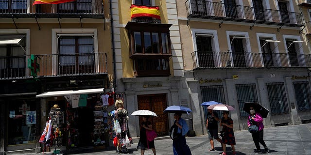 Tourists shelter under umbrellas during a heatwave in Toledo, Spain, on June 28, 2019. 