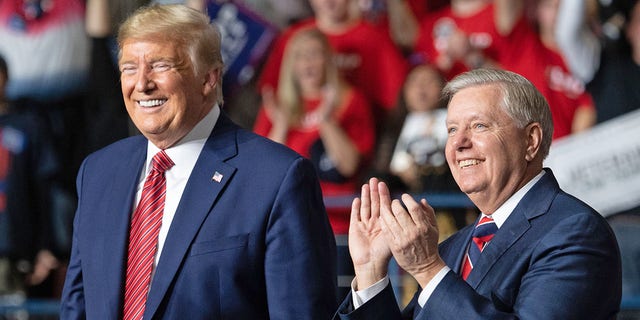 President Trump, left, smiles as he stands alongside Republican Sen. Lindsey Graham of South Carolina during a Trump campaign rally at the North Charleston Coliseum in North Charleston, S.C., Feb. 28, 2020. 