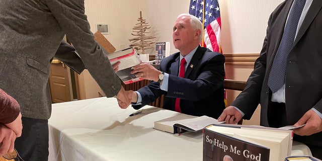 Former Vice President Mike Pence signs copies of his new autobiography "So Help Me God," at a book signing on Dec. 12, 2022 in Bedford, New Hampshire.