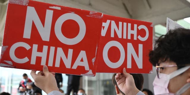 A pro-Taiwan independence activist displays placards during a protest before Chinas Taiwan Affairs officials arrive in Taipei on Feb. 18, 2023. 