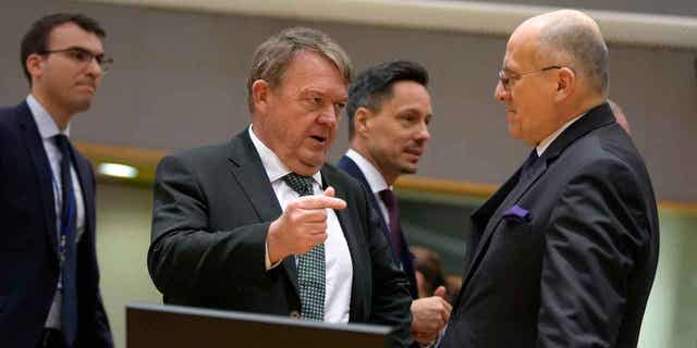 Denmark's Foreign Minister Lars Lokke Rasmussen, center, speaks with Poland's Foreign Minister Zbigniew Rau, right, in Brussels on Feb. 20, 2023. European Union foreign ministers imposed sanctions on nine Burma officials linked to rising violence and human rights violations.