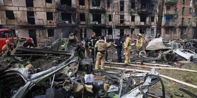 Emergency workers inspect a damaged apartment 