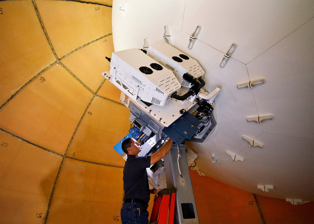 A Globalstar employee on a ladder working on a ground base unit