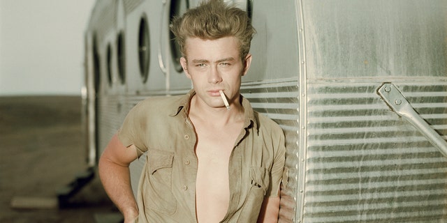 James Dean posing next to trailer with cigarette in his mouth