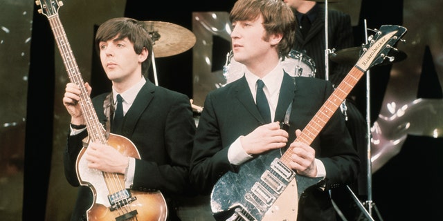 Paul McCartney and John Lennon hold their guitars on The Ed Sullivan Show