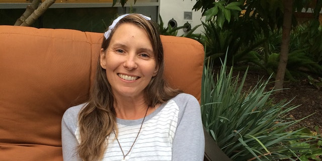 Wendi Lou Lee smiling with a striped grey and white long sleeved sweater