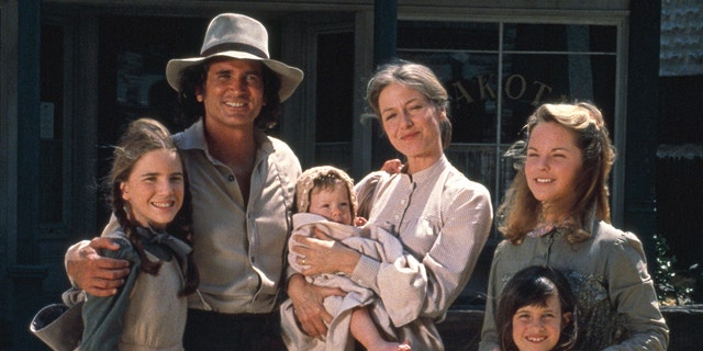 The cast of Little house in costume smiling and facing the camera