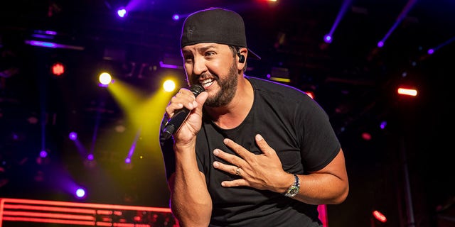 A photo of Luke Bryan singing in concert