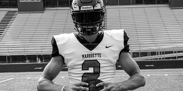 Jordan DeMay holding a football in black/white photo