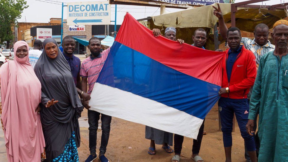Coup supporters unfurl a Russian flag as they take to the streets after the army seized power in Niamey, Niger