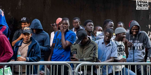 Migrants await registration outside of the Roosevelt Hotel