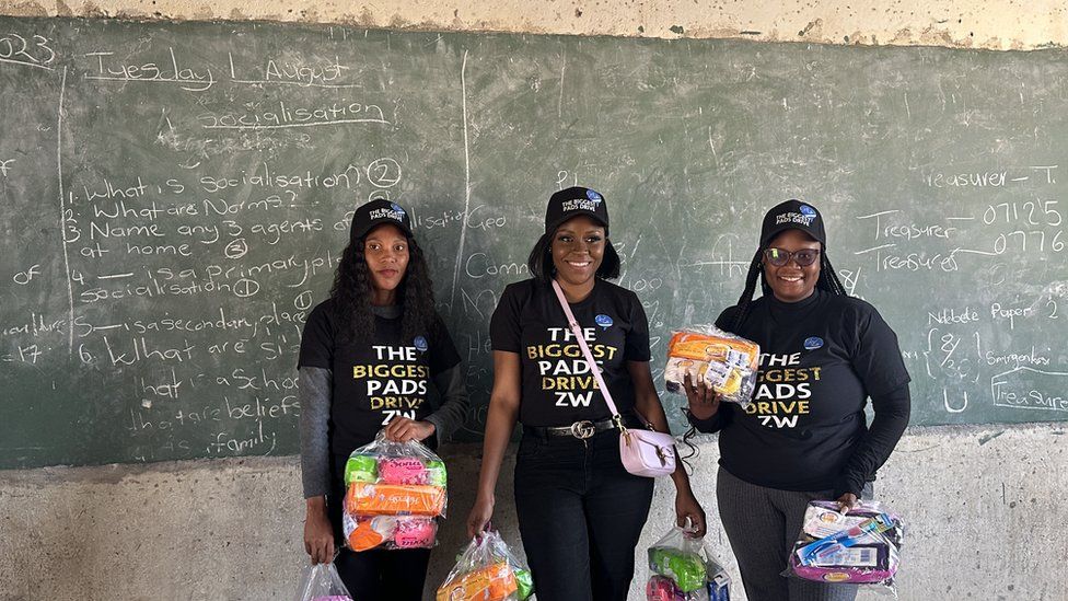 Three women holding sanitary pads