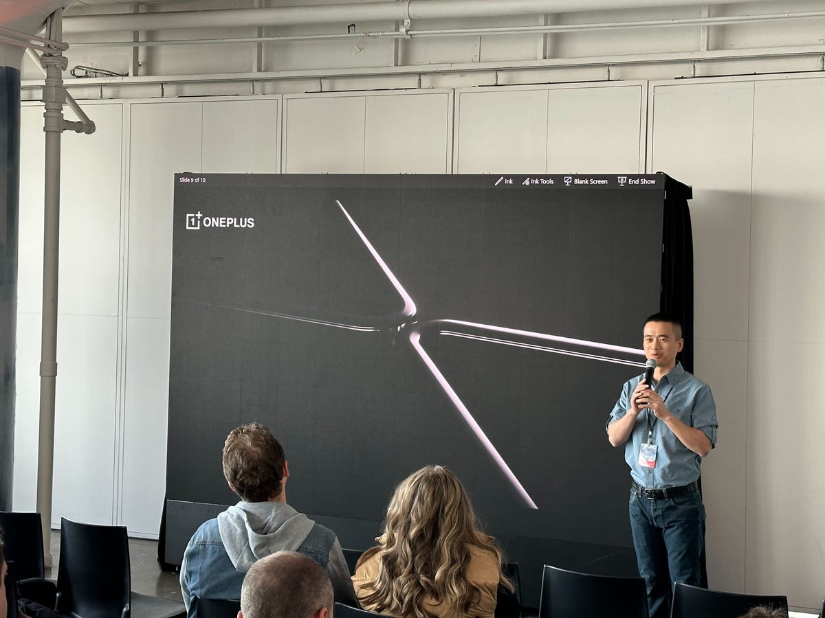 A man standing in front of a photo of a foldable phone