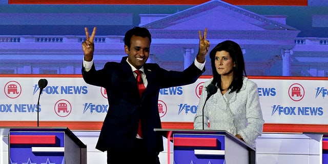 Ramaswamy puts up the peace sign to the audience next to Haley on the debate stage