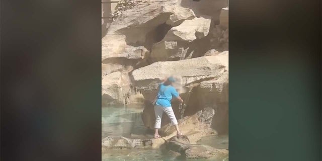 Woman fills water bottle at Trevi Fountain
