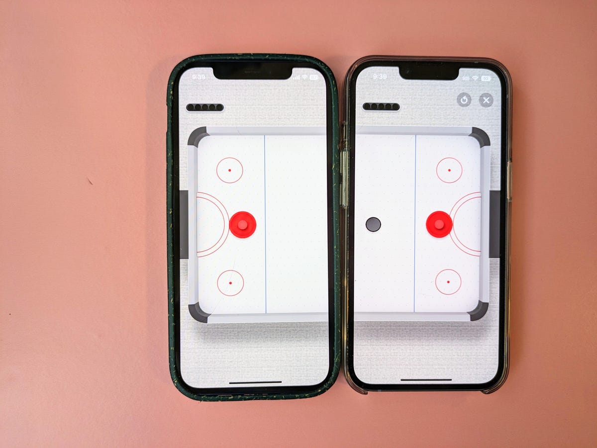 An air hockey video game being shown on two iPhones.