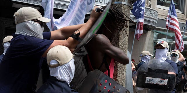 members of Patriot Front shove Black man with shields