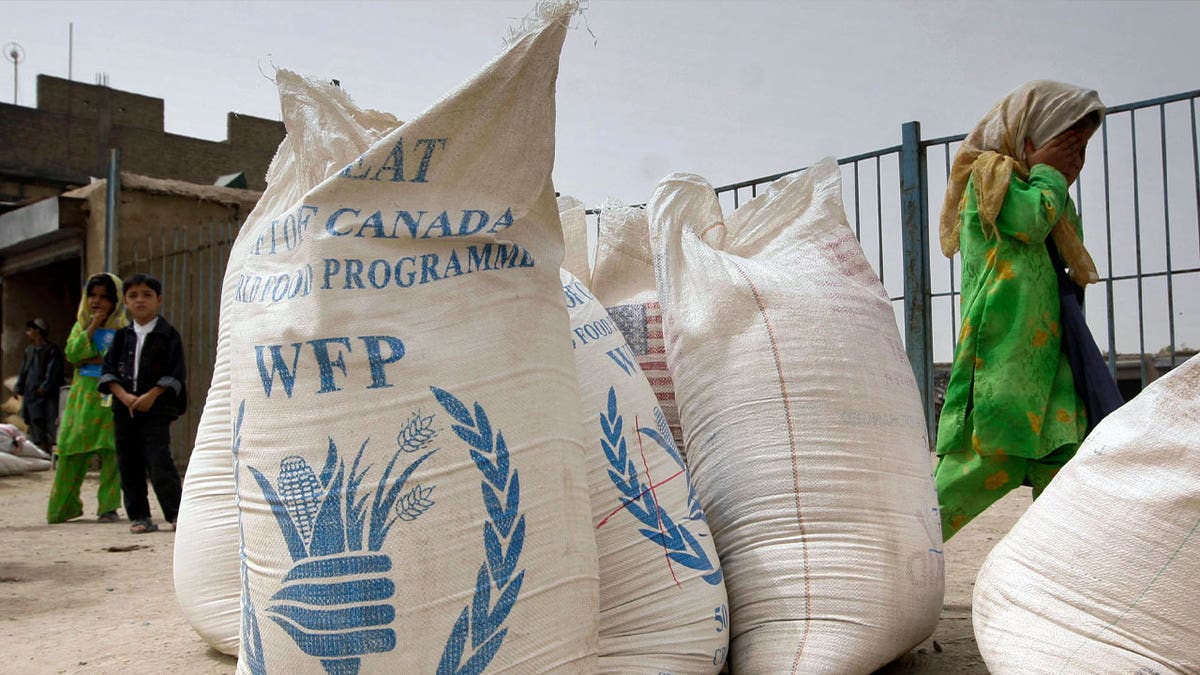 girl walks past sacks of wheat