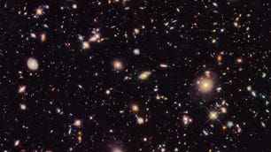 A spray of galaxies and stars looking small against the darkness of space.