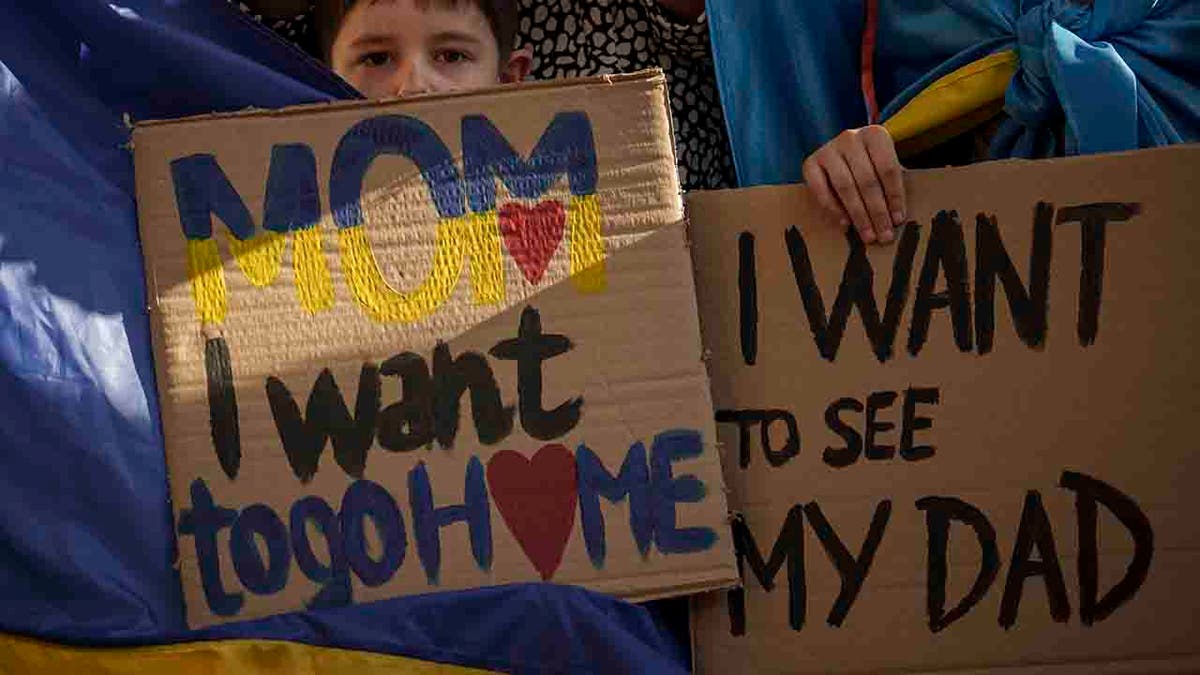 Ukrainian children hold banners