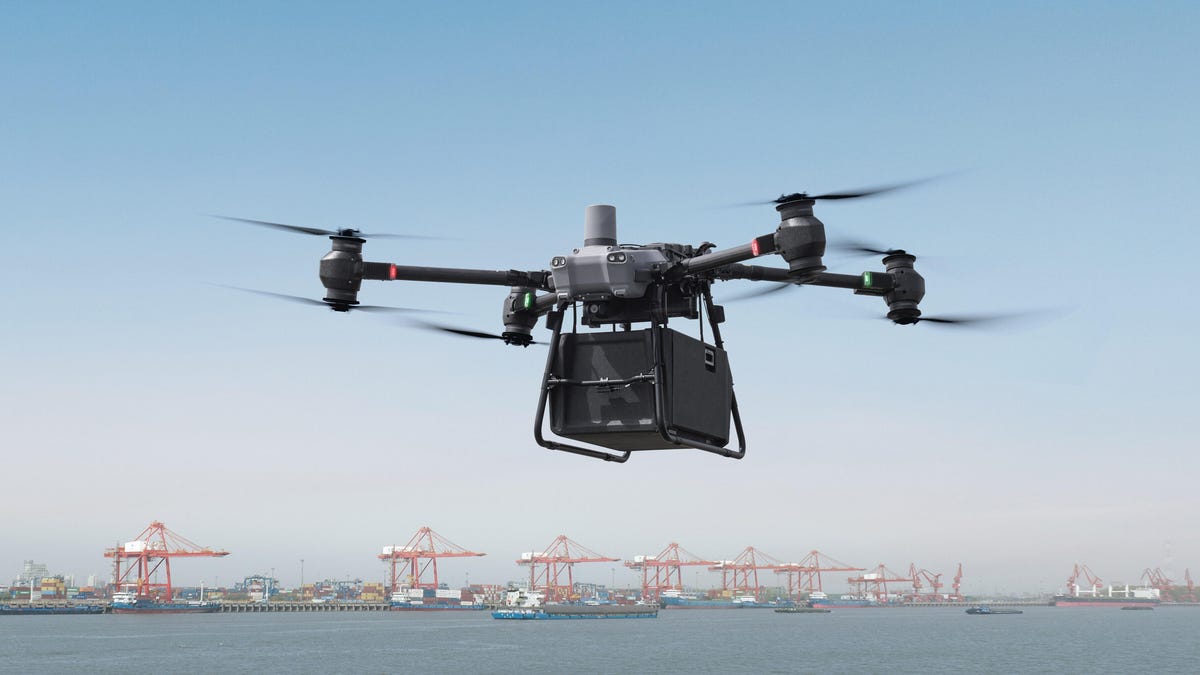 DJI's Flycart 30 drone carrying a large box with a shipping port in the background