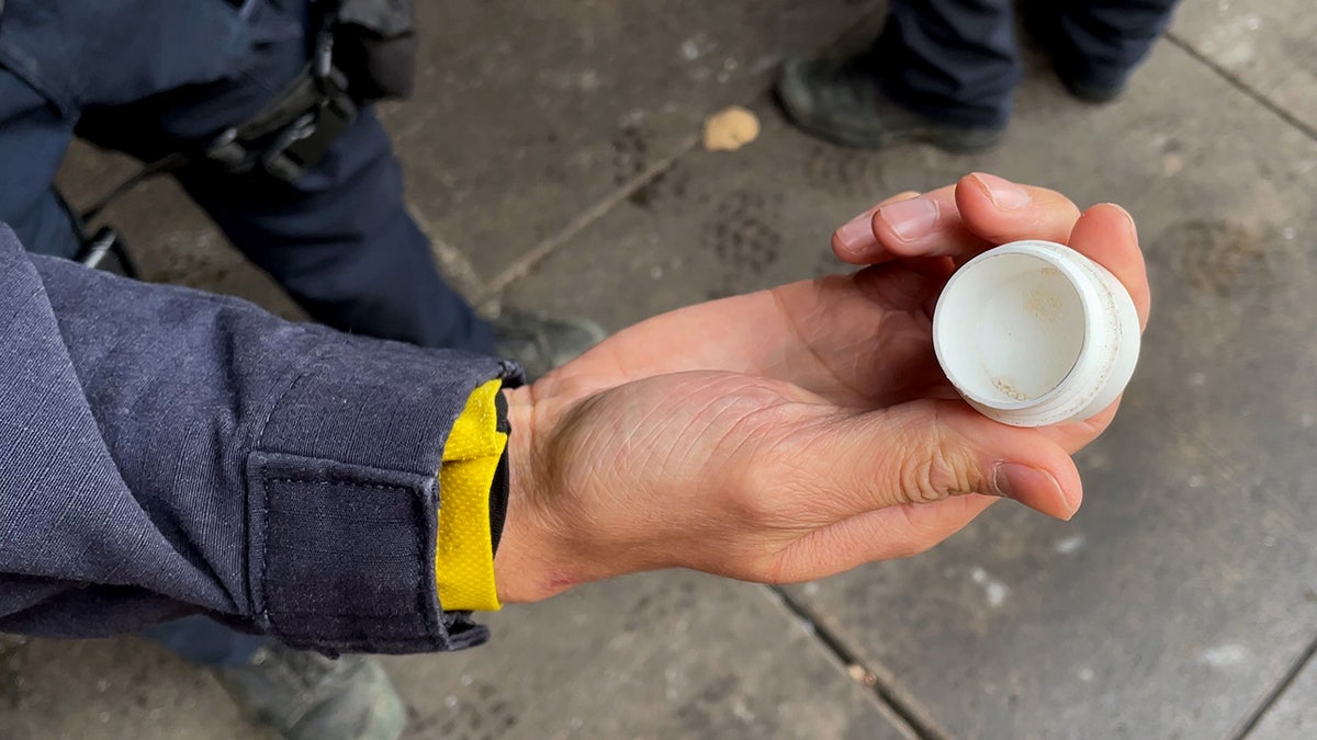 Hand holding white container with small amount of white powder inside