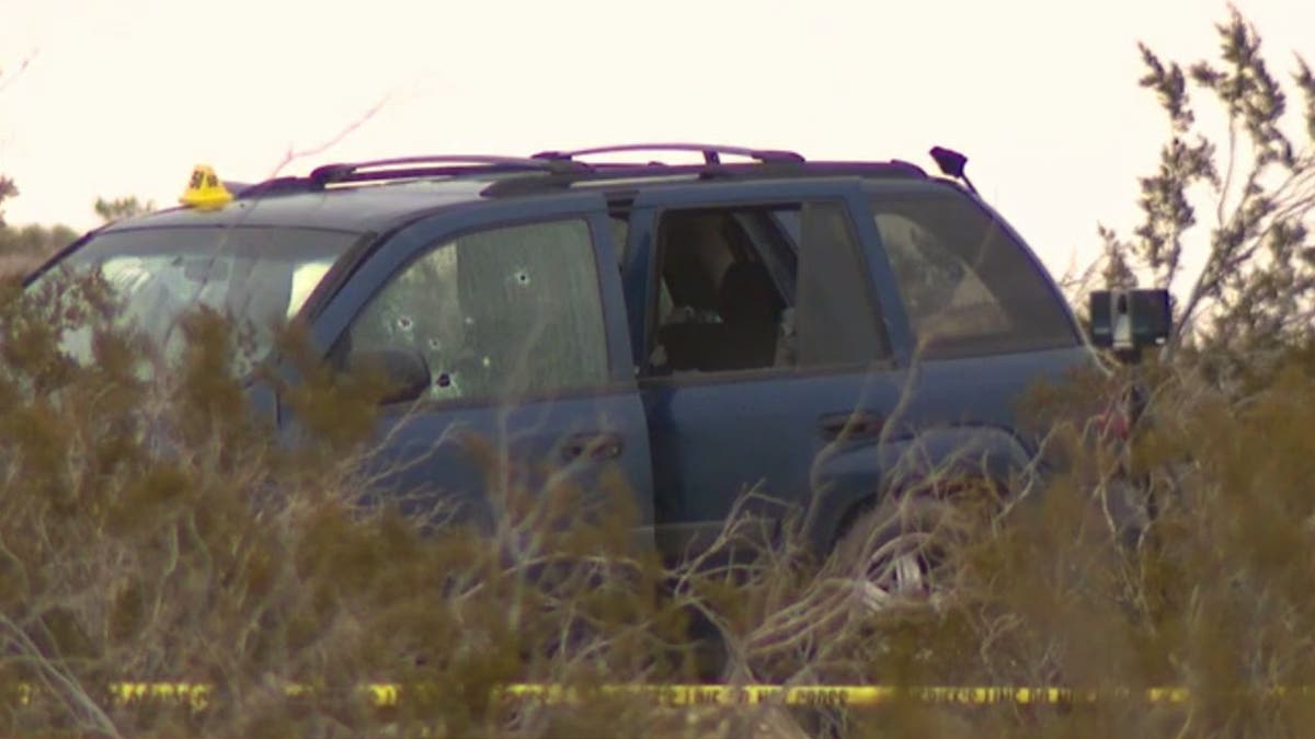 A navy-colored mini SUV, riddled with bullet holes.