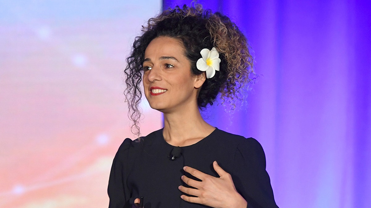 Iranian dissident Masih Alinejad smiles on stage while gesturing with her hand