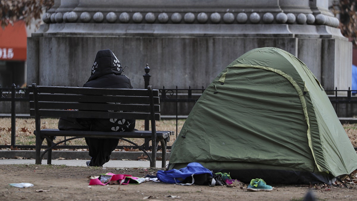 Person sitting on a bench, a tent