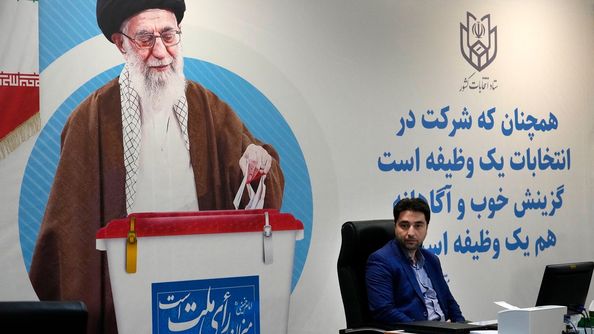 A staff of elections headquarters sits beside a giant portrait of the Iranian Supreme Leader Ayatollah Ali Khamenei, during the registration of candidates for the June 28 presidential elections at the Interior Ministry in Tehran, Iran.