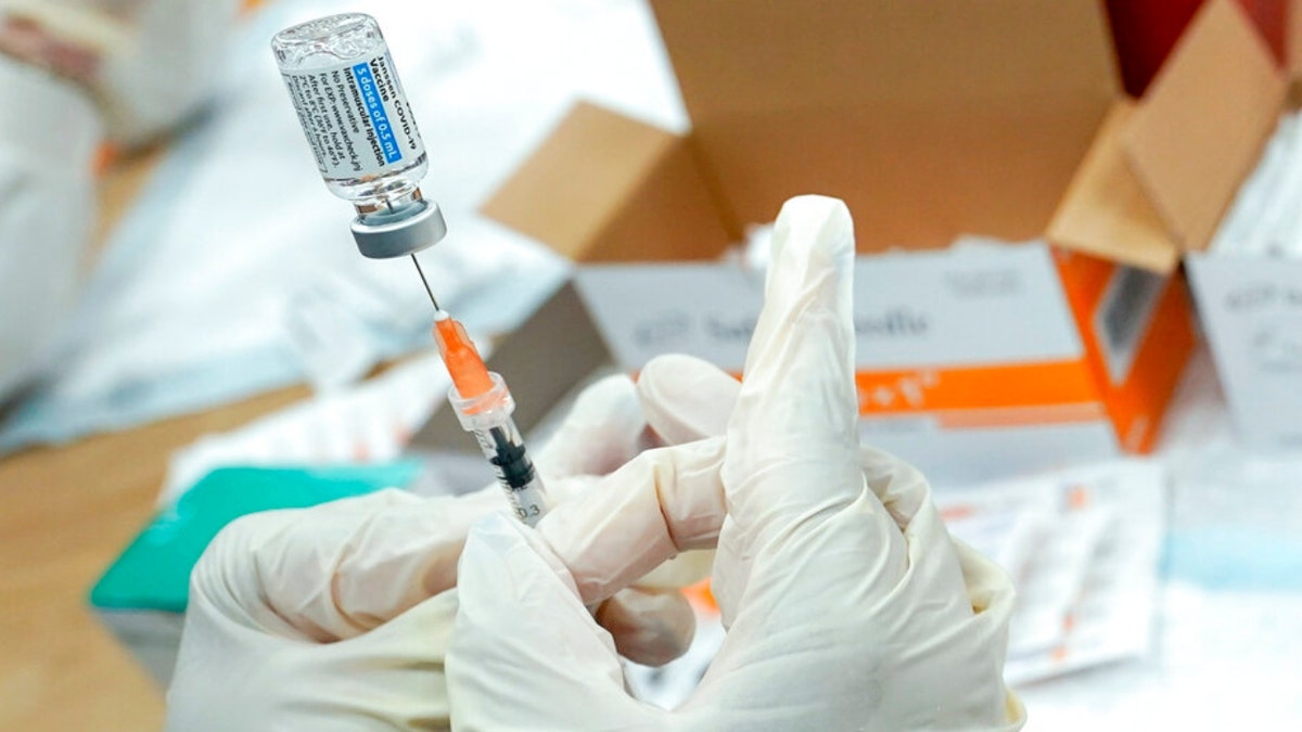 A registered nurse fills a syringe with the COVID-19 vaccine