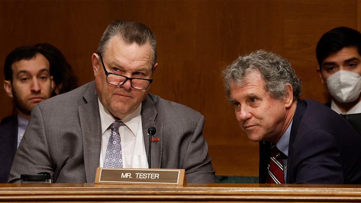 Senate Banking, Housing and Urban Affairs Committee Chairman Sherrod Brown (D-OH), right, talks with committee member Sen. Jon Tester (D-MT) during a hearing about the Consumer Financial Protection Bureau.