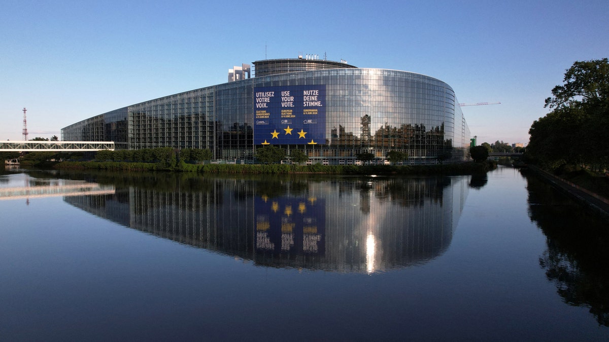 The European Parliament building is reflected on the still water in France.