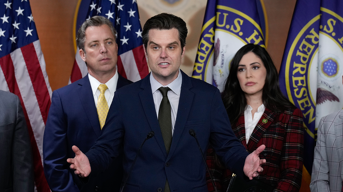 Reps. Matt Gaetz, center, and Luna, right, in front of flags