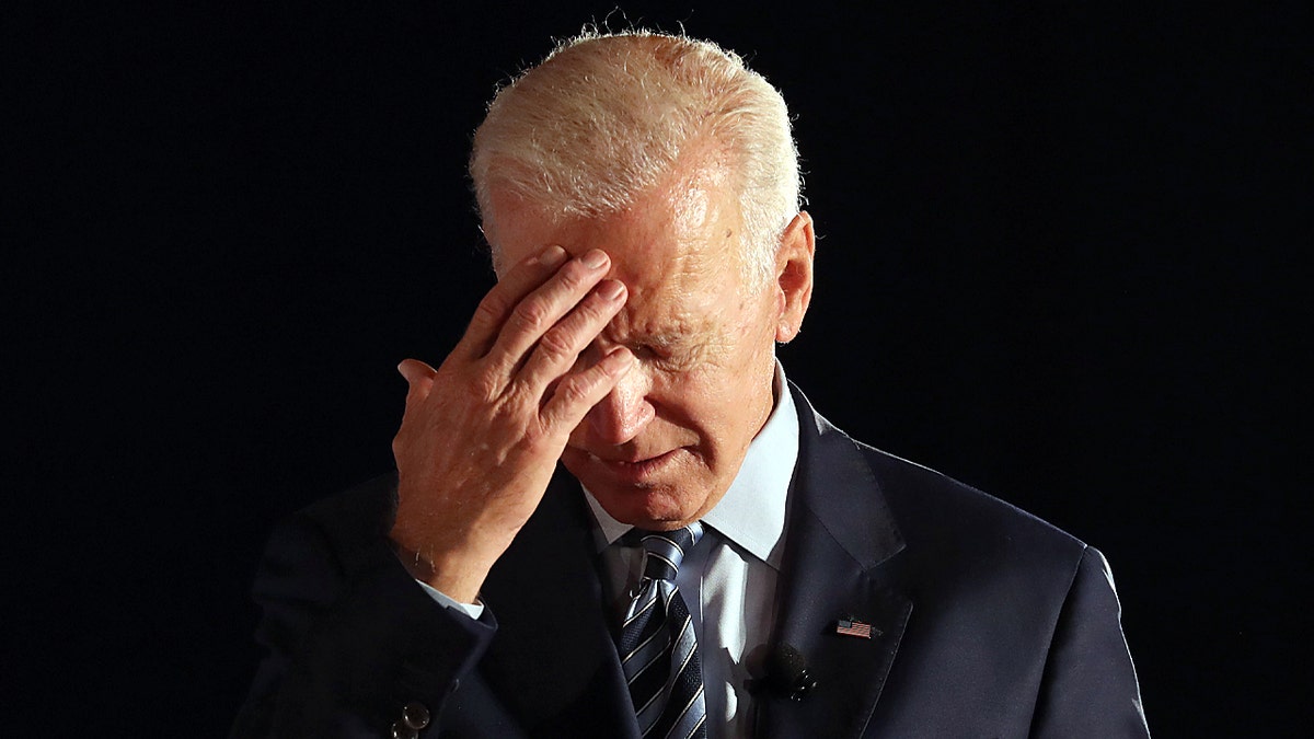 Biden bowing head with hand on forehead