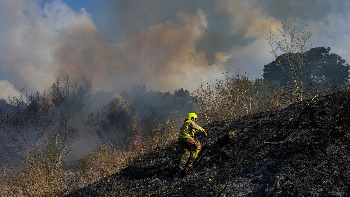 A firefighter works in the area around a fire