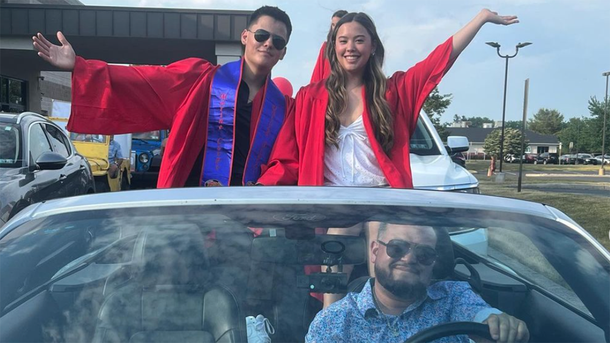 Collin and Hannah Gosselin in red gowns stand up in their dad Jon's convertible