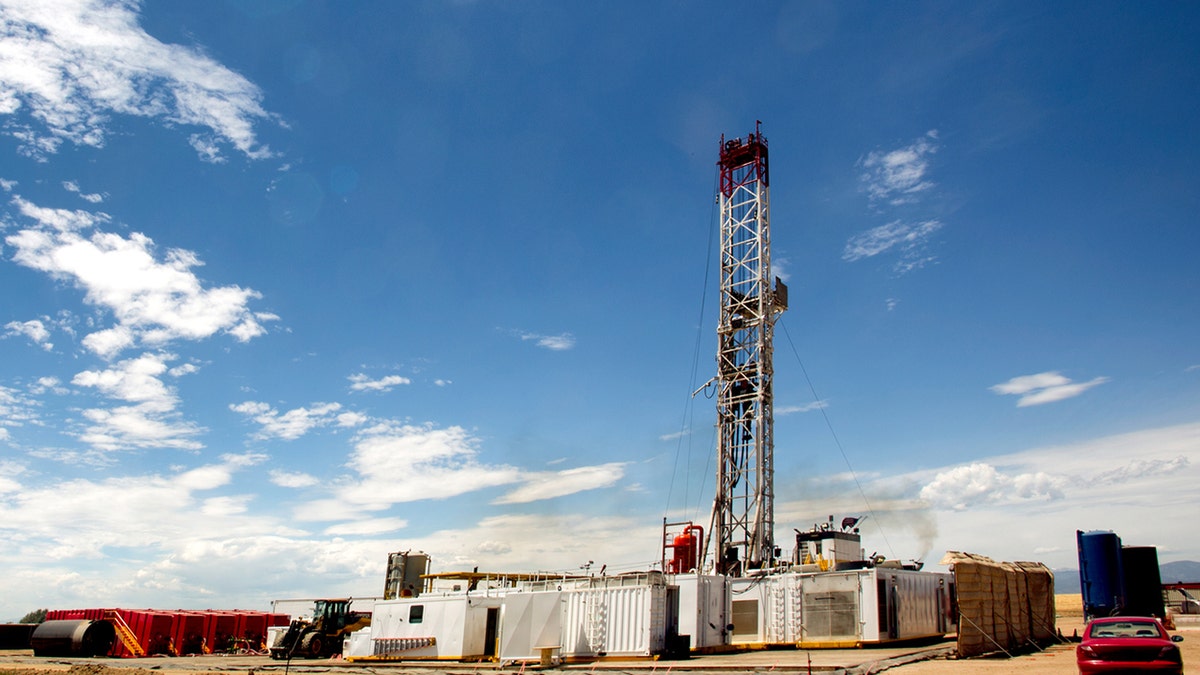 Fracking Drill Rig in a remote location in the mountains with wispy clouds in the sky at dusk. Fracking Rig is performing a fracking operation to liberate trapped crude oil and natural gas into the pipeline to a refinery.