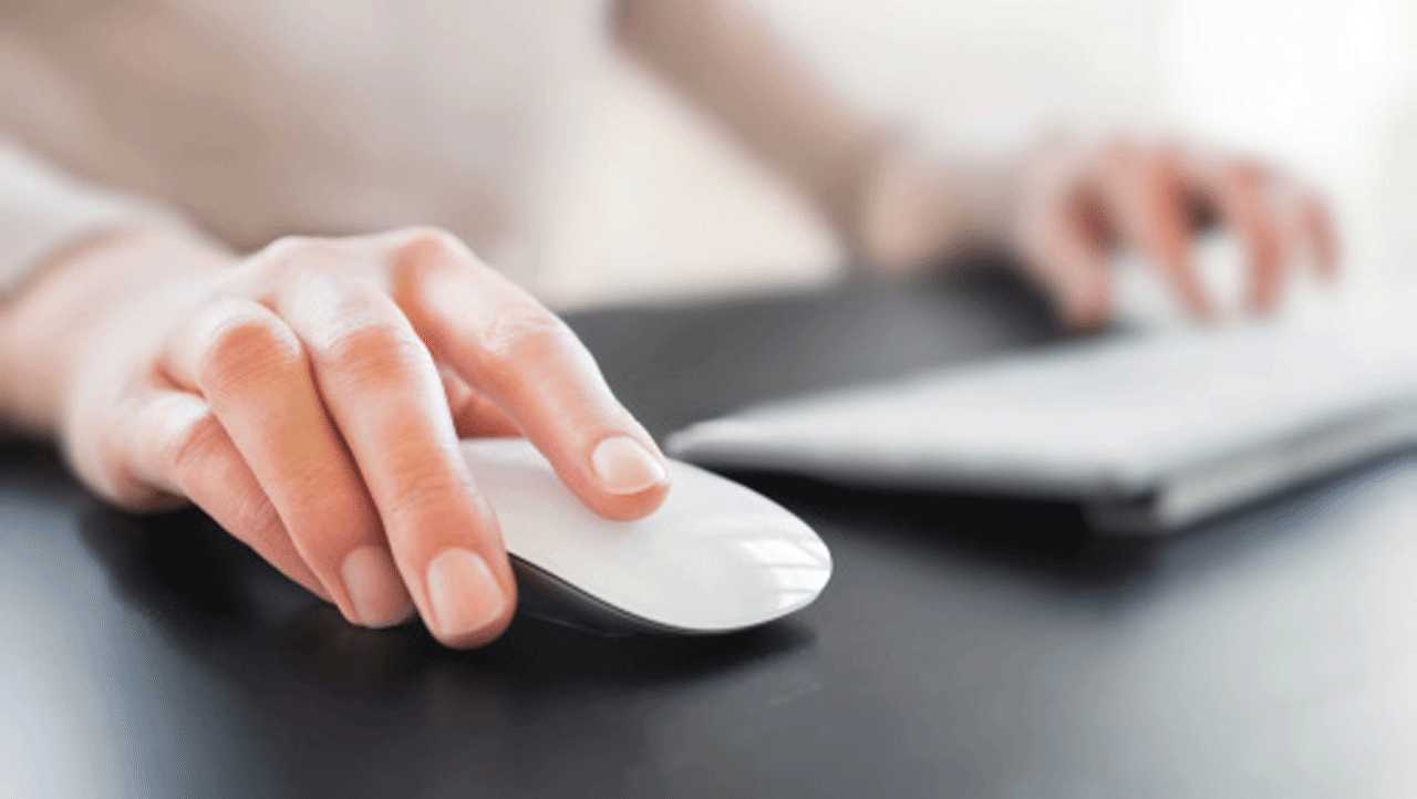 womans hand on a computer mouse and keyboard