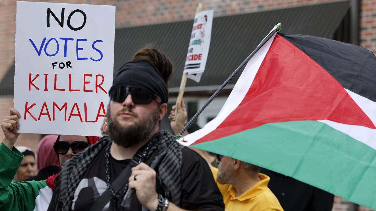 protesters with sign reading "no votes for killer Kamala"