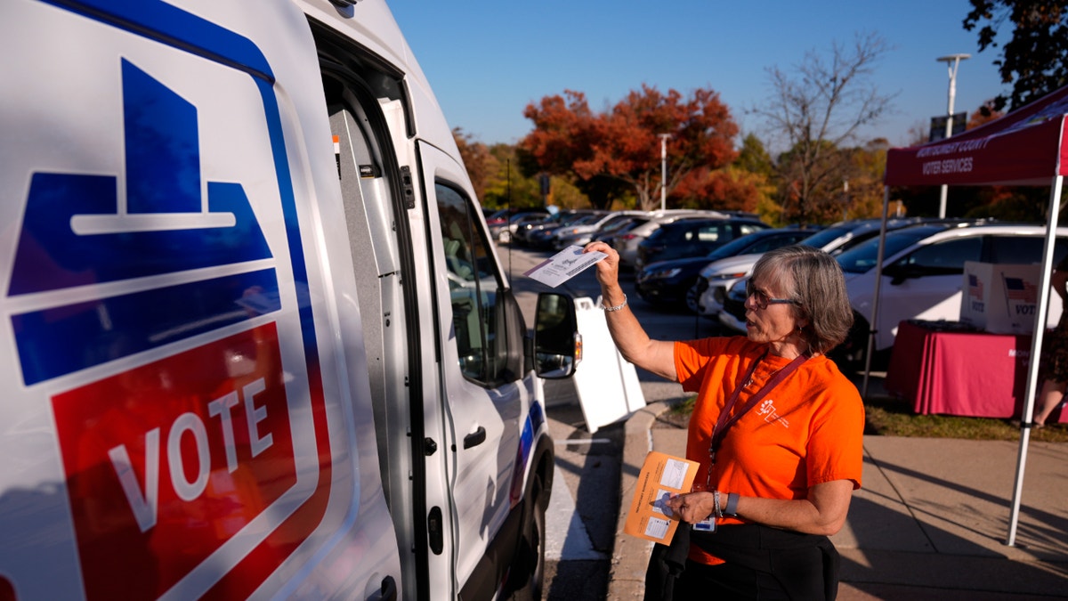 woman with mail-in ballot by van