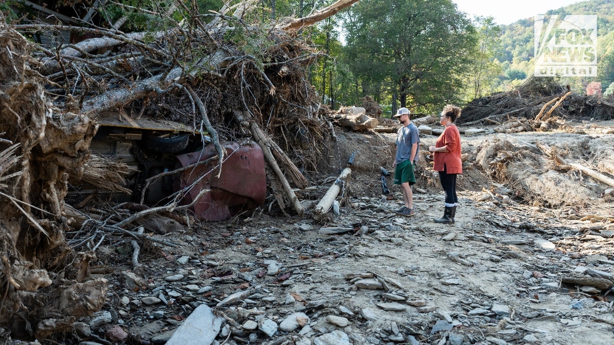 Jesse and Mekenzie Craig stand by the roots of an overturned tree that fell on Jesse's parents' house